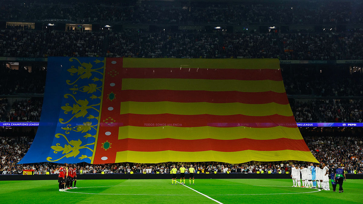 Bandera de Valencia en las gradas mientras se ven a los jugadores durante un minuto de silencio en memoria de las víctimas de las inundaciones en Valencia - REUTERS/ SUSANA VERA