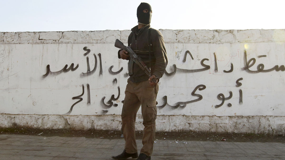 Un combatiente del Ejército Libre Sirio porta su arma frente a un grafiti con la leyenda Daesh en el barrio de Masaken Hanano, Alepo - REUTERS//JALAL ALHALABI