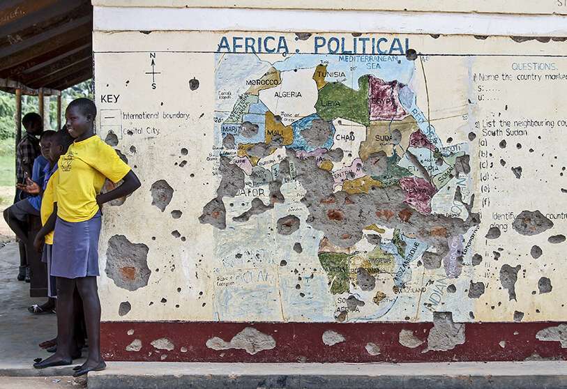Los estudiantes se alinean fuera de un aula con un mapa de África en su pared, en Yei, en el sur de Sudán del Sur