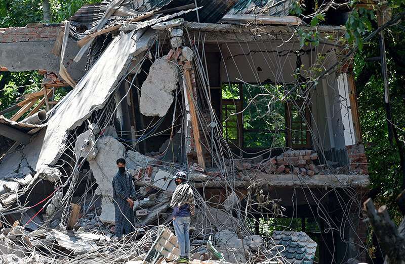 Aldeanos de Cachemira entre los escombros de una casa destruida durante un tiroteo entre militantes y fuerzas gubernamentales indias en la aldea de Panjran en Pulwama, al sur de Srinagar, el 7 de junio de 2018