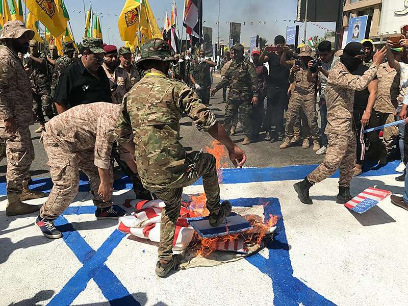 Fotografía de archivo del 31 de mayo de 2019, las Unidades de Movilización Popular iraquíes queman representaciones de banderas de Estados Unidos e Israel