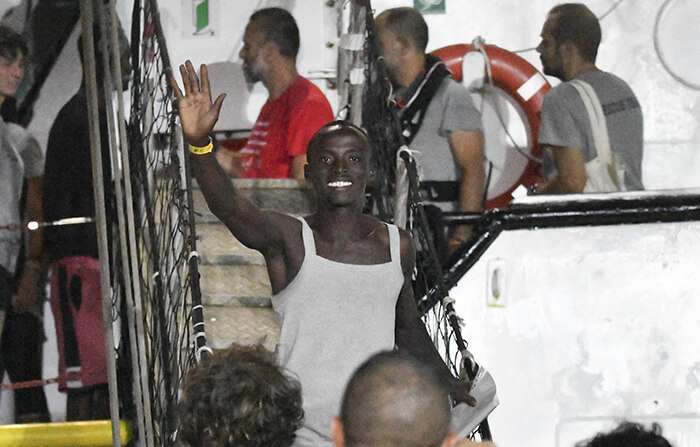 Un migrante saluda al desembarcar del barco de rescate Open Arms en la isla siciliana de Lampedusa, al sur de Italia, el martes 20 de agosto de 2019