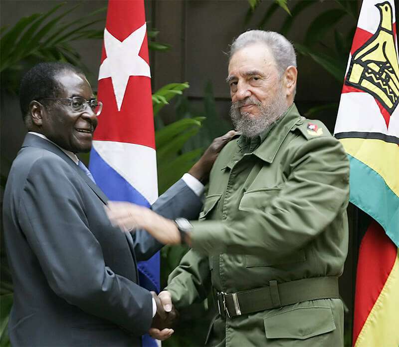 En esta foto de archivo tomada el 12 de septiembre de 2005 el presidente cubano Fidel Castro (D) da la mano a Robert Mugabe, entonces presidente de Zimbabue, en el Consejo de Estado de La Habana