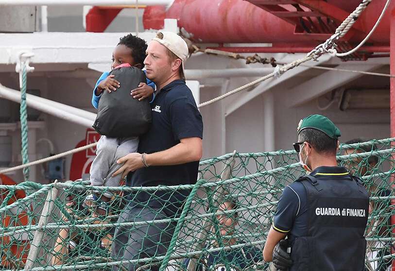 Un niño es llevado en brazos al desembarcar del Ocean Viking, atracado en el puerto siciliano de Messina, al sur de Italia, el martes 24 de septiembre de 2019