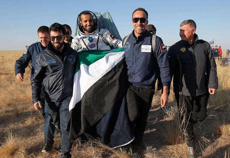 Miembros del equipo de rescate de la Agencia Espacial Rusa y especialistas de Emiratos Árabes Unidos transportan al astronauta Hazza al-Mansoori