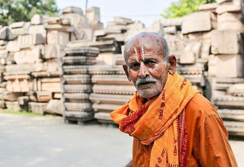 Un devoto pasa junto a los pilares que el grupo nacionalista hindú Vishva Hindu Parishad (VHP) dice que serán usados para construir un templo Ram en el sitio religioso disputado en Ayodhya, India, el 22 de octubre de 2019.