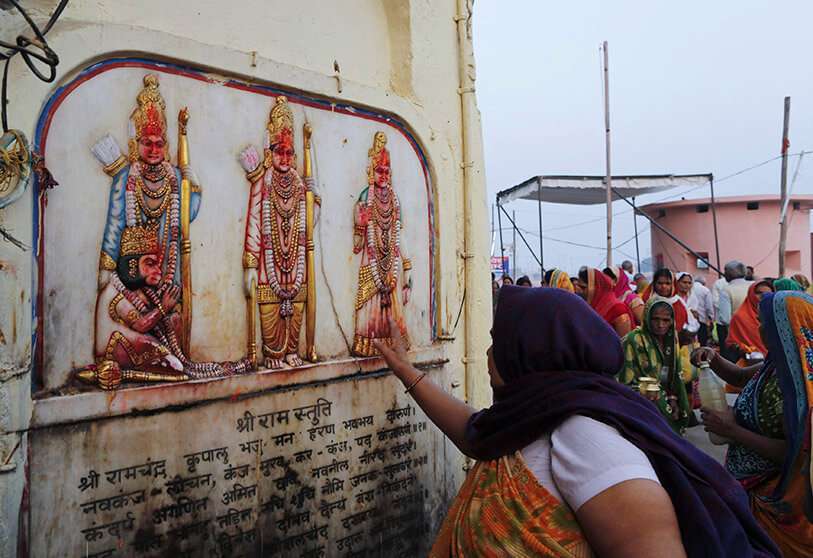 Un peregrino hindú toca en reverencia una imagen del dios hindú Rama, su esposa Sita y su hermano Lakshman en Ayodhya, India, el sábado 9 de noviembre de 2019.