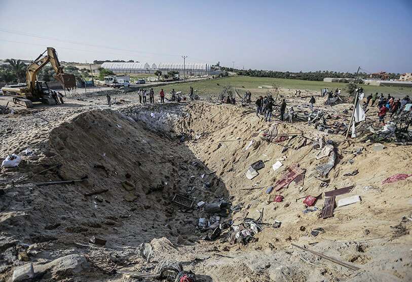 Palestinos inspeccionan un cráter hecho por un misil israelí que destruyó una casa y mató a ocho miembros de la familia Abu Malhous en Deir al-Balah