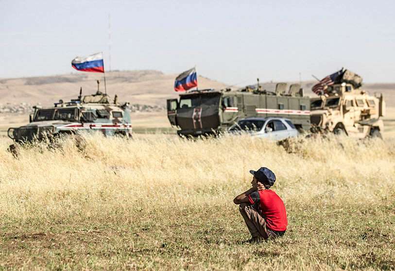 Un niño sirio observa los vehículos militares rusos y estadounidenses en la ciudad siria nororiental de al-Malikiyah (Derik), en la frontera con Turquía, el 3 de junio de 2020