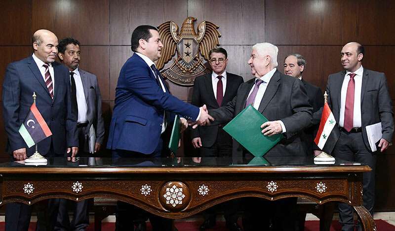 En una foto publicada por la Agencia Oficial de Noticias Árabes Sirias (SANA) el 1 de marzo de 2020, el ministro de Relaciones Exteriores de Siria, Walid al-Moallem (C-R), y el ministro de Relaciones Exteriores del gobierno del Ejército de Liberación Nacional libio, Abdulhadi Lahweej (C-L), firman un acuerdo conjunto en la capital siria, Damasco.