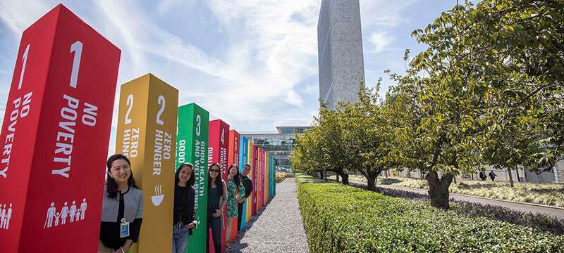 ONU/Laura Jarriel - Jóvenes se alinean junto a una instalación con los símbolos de los 17 Objetivos de Desarrollo Sostenible