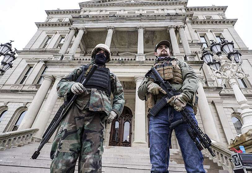 Des hommes armés se tiennent sur les marches du Capitole de l'État après un rassemblement de soutien au président Donald Trump à Lansing, Michigan