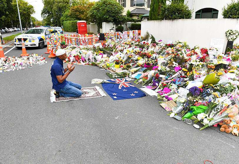 PHOTO/MICK TSIKAS/AAP New Zealand, Christchurch: A man prays in front of flowers and pays tribute to the victims of attacks on mosques 