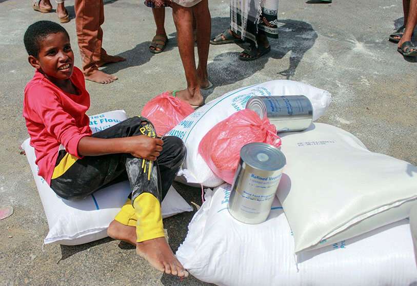 Un joven junto a los artículos de ayuda alimentaria distribuidos por los empleados del Programa Mundial de Alimentos (WFP) en la capital de Yemen, Sanaa, el 18 de abril de 2020