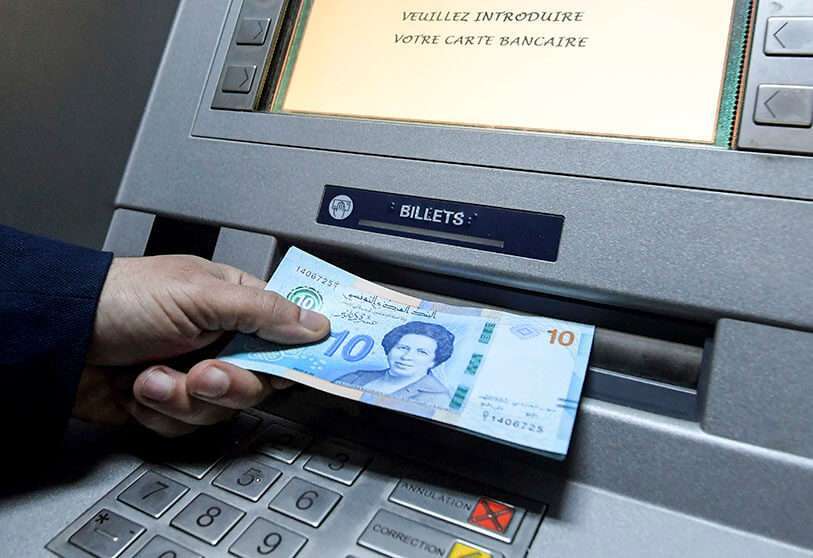 Un hombre retira unos billetes de banco tunecino