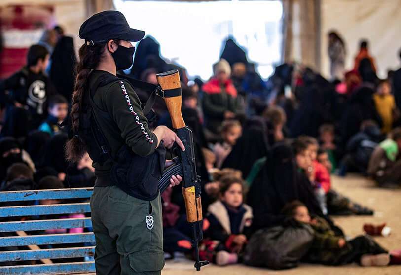 AFP/DELIL SOULEIMAN-Un guardia vigila mientras los sirios esperan para salir del campamento de Al-Hol, gestionado por los kurdos, que alberga a familiares de presuntos combatientes del EI en Al-Hasakeh.
