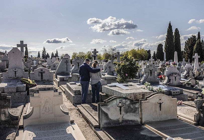Dos personas con máscaras faciales para protegerse del coronavirus asisten al entierro de un pariente en un cementerio de Madrid durante el brote de coronavirus en Madrid, España, el viernes 27 de marzo de 2020