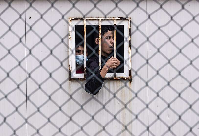 Menores no acompañados que cruzaron a España se reúnen fuera de un almacén utilizado como refugio temporal mientras esperan ser examinados para el COVID-19  AP/BERNAT ARMANGUE