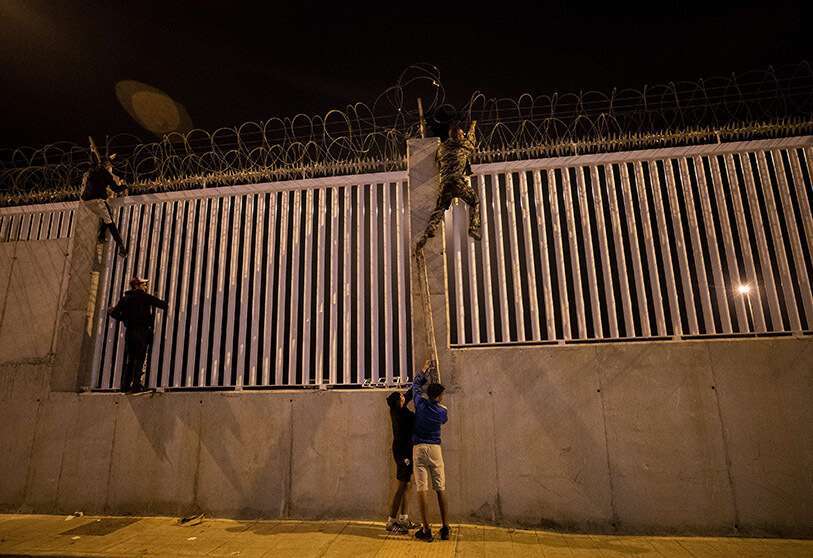 Migrantes que recientemente han cruzado la frontera entre España y Marruecos, cruzan en el puerto comercial de Ceuta, España, el miércoles 19 de mayo de 2021. El grupo explicó a The Associated Press su objetivo de llegar a los puertos europeos de Málaga o Algeciras tras esconderse dentro de un barco comercial AP/BERNAT ARMANGUE