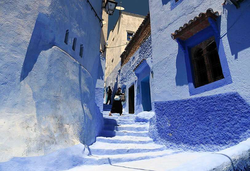 Una mujer camina a lo largo de un pequeño callejón en la ciudad marroquí noroccidental de Chefchaouen, en las montañas del Rif