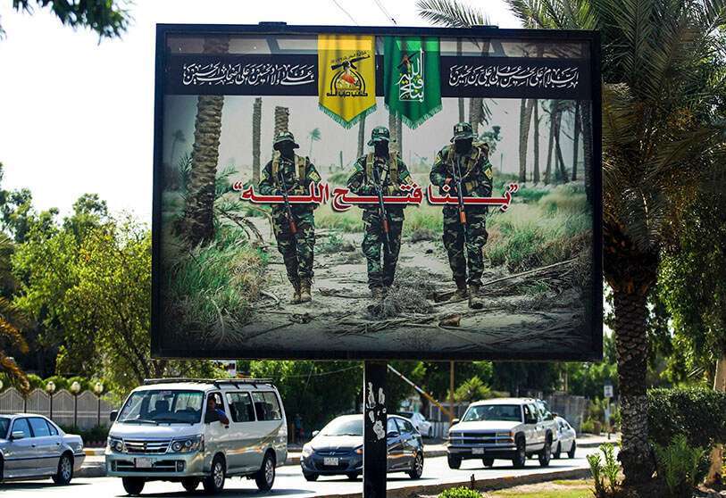 Valla publicitaria de propaganda de la milicia pro-iraní de las Brigadas de Hizbolá que cuelga sobre la calle Palestina en el centro de la capital iraquí, Bagdad, en la que aparecen tres de sus combatientes enmascarados