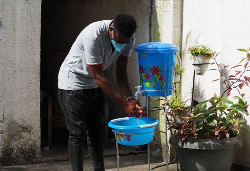 Un jeune homme se lave les mains à l'eau et au savon à Kinshasa