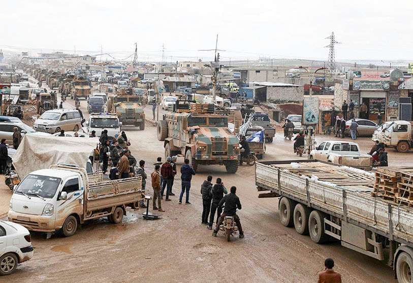Residentes observan cómo un convoy militar turco que cruzó la frontera con Siria pasa a través de la ciudad de Hazano, en la campiña norteña de Idlib, el 22 de febrero de 2020