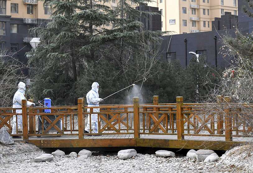AP/WAMG XIAO/ XINHUA-Trabajadores con trajes protectores rocían desinfectante cerca de un área residencial en Shijiazhuang, en la provincia de Hebei, al norte de China, el miércoles 13 de enero de 2021 