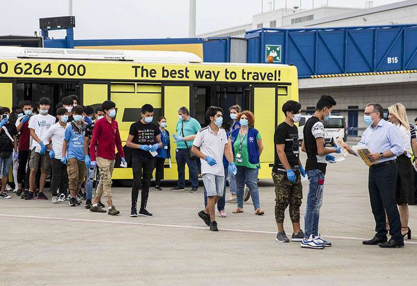 PHOTO/AP - El viceministro de Migración, Giorgos Koumoutsakos, a la derecha, saluda a los 25 niños refugiados no acompañados mientras se preparan para subir a un avión con destino a Lisboa, Portugal, en el aeropuerto internacional de Atenas, el martes 7 de julio de 2020