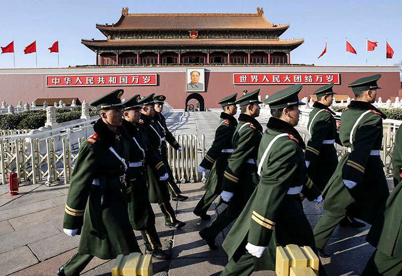 Policías paramilitares pasan junto a un retrato del difunto líder chino Mao Zedong en la entrada principal de la Ciudad Prohibida