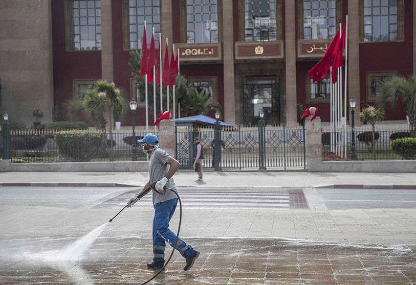 Un trabajador desinfecta una avenida principal fuera del edificio del Parlamento, en Rabat, Marruecos, el miércoles 18 de marzo de 2020