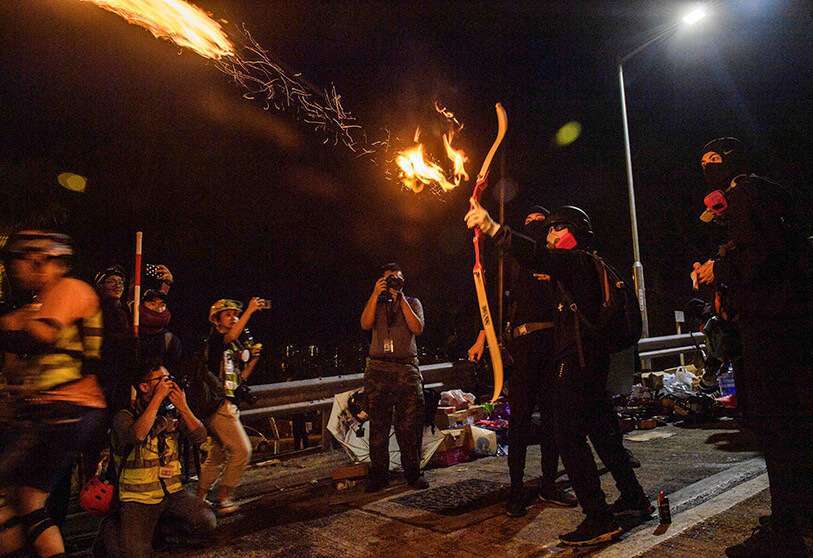 Un manifestante lanza una flecha de fuego con su arco para encender una barricada en la Universidad China de Hong Kong (CUHK), en Hong Kong, a principios del 13 de noviembre de 2019