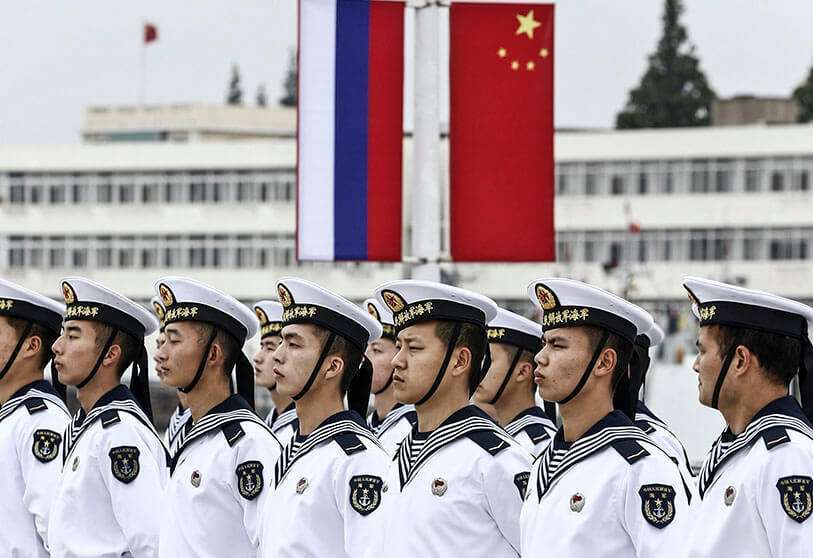 Marineros chinos en formación frente a las banderas nacionales de Rusia y China en el puerto de Shanghái, mientras se preparan para la ceremonia de bienvenida a los buques de la Armada rusa antes de unas maniobras conjuntas