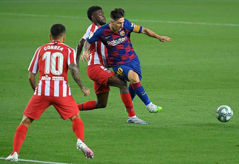 El delantero argentino del Barcelona Lionel Messi (D) desafía al centrocampista ghanés Thomas Partey del Atlético de Madrid y al delantero argentino del Atlético de Madrid Ángel Correa (L) durante el partido de fútbol de la Liga Española entre el FC Barcelona y el Club Atlético de Madrid en el estadio Camp Nou de Barcelona el 30 de junio de 2020.