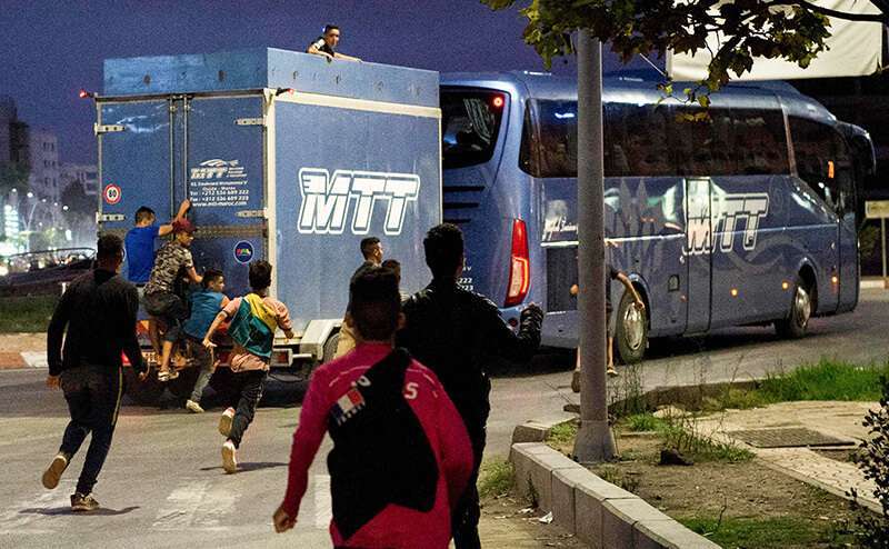 Jóvenes migrantes marroquíes sin hogar intentan viajar a Europa saltando en la parte trasera de un vehículo en la ciudad portuaria de Nador en Marruecos, con la esperanza de encontrar un mejor nivel de vida