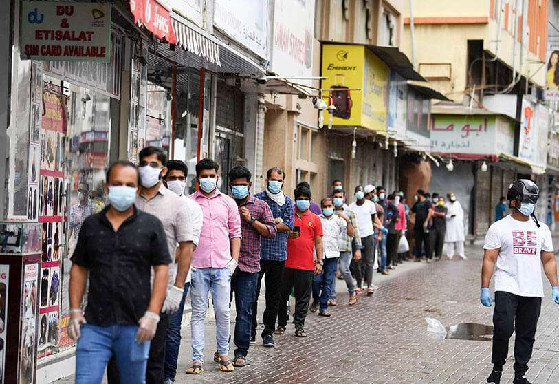 Trabajadores extranjeros hacen cola mientras esperan a ser examinados para detectar el nuevo coronavirus en un centro de pruebas en la zona de Naif, Dubái