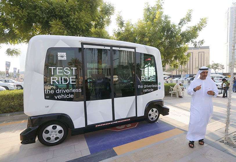 Un hombre que camina cerca de un coche autónomo de diez plazas durante un recorrido de prueba a lo largo del bulevar Mohammed bin Rashid