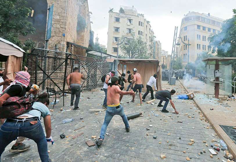 PHOTO/AFP - Manifestantes libaneses lanzan piedras hacia las fuerzas de seguridad durante los enfrentamientos en el centro de Beirut el 8 de agosto de 2020, tras una manifestación contra un liderazgo político al que culpan de la explosión que mató a más de 150 personas en la capital Beirut
