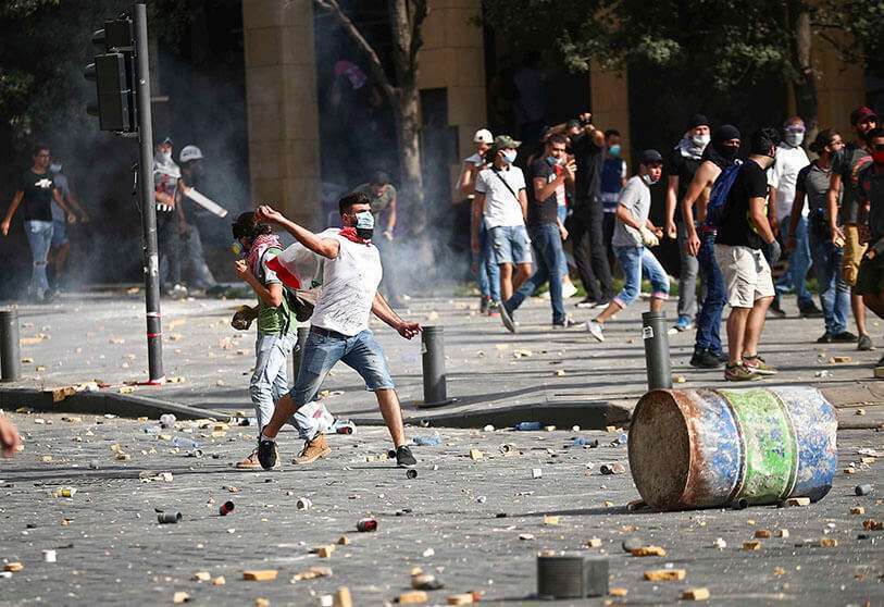 REUTERS/HANNAH McKAY - Un manifestante arroja piedras durante una protesta cerca del edificio del parlamento después de la explosión del martes, en Beirut, Líbano 8 de agosto de 2020