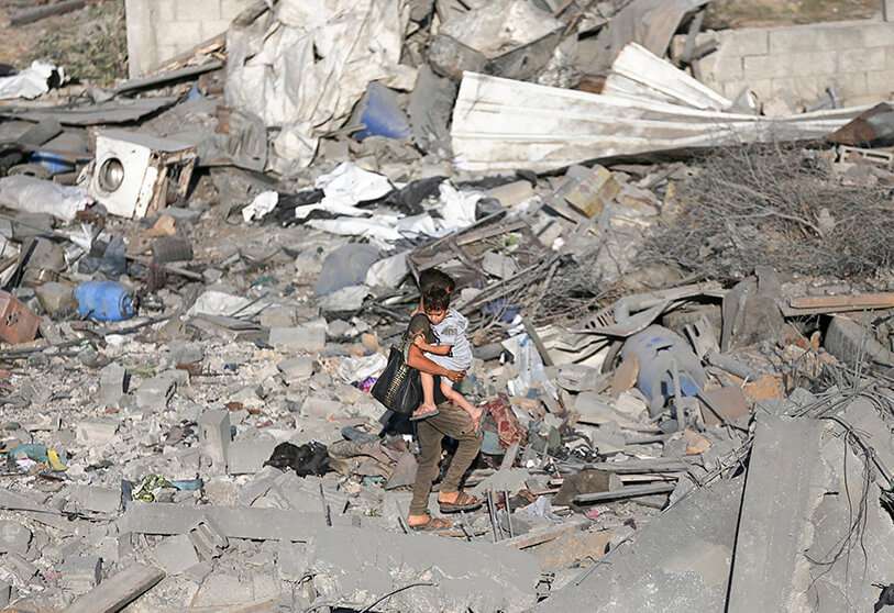 Un niño palestino carga a su hermano mientras camina entre los escombros de una casa destruida en un ataque aéreo israelí en el sur de la Franja de Gaza el 14 de noviembre de 2019.
