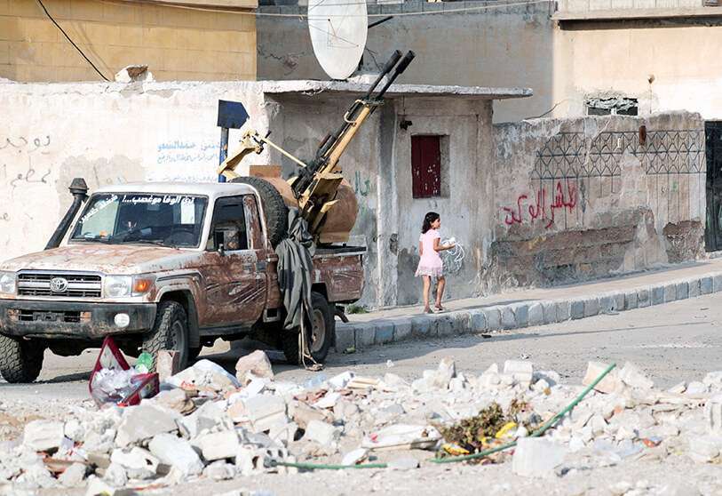 Una niña camina cerca de un camión montado con un arma en la ciudad fronteriza de Tal Abiad, Siria, el 17 de octubre de 2019