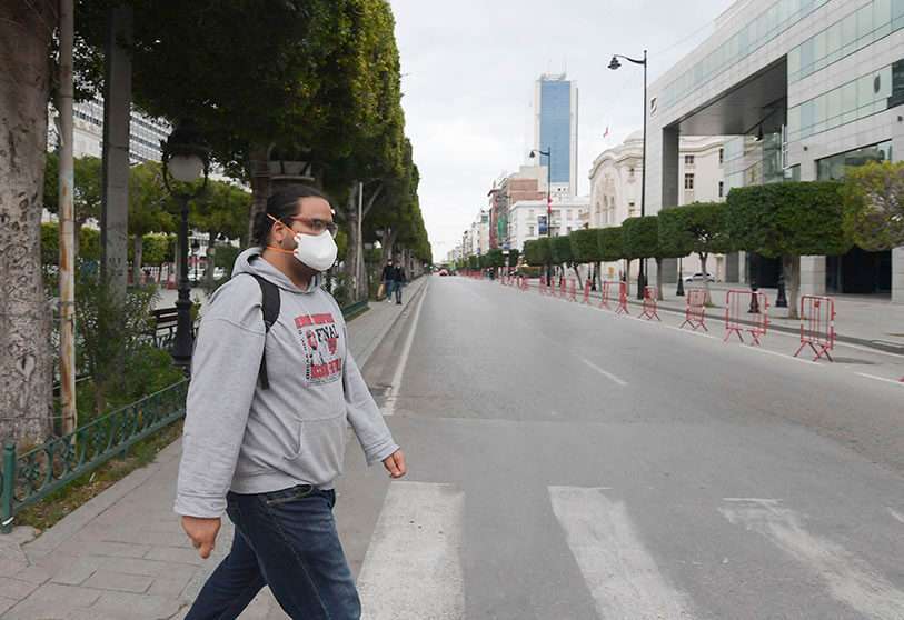 Un hombre con una máscara facial cruza una calle de la avenida Habib Bourguiba en Túnez el 18 de marzo de 2020, poco antes del toque de queda nocturno