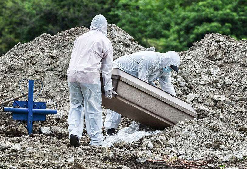 Hombres en trajes protectores entierran el ataúd de un pariente que murió de COVID-19, en las afueras de Tegucigalpa el 12 de junio de 2020