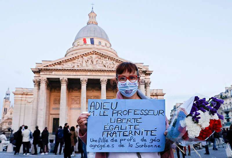 Una mujer sostiene una pancarta en la que se lee "Adiós Sr. Maestro" en la plaza del Panteón de París el 21 de octubre de 2020, durante un homenaje nacional en la Universidad de la Sorbona al maestro francés Samuel Paty