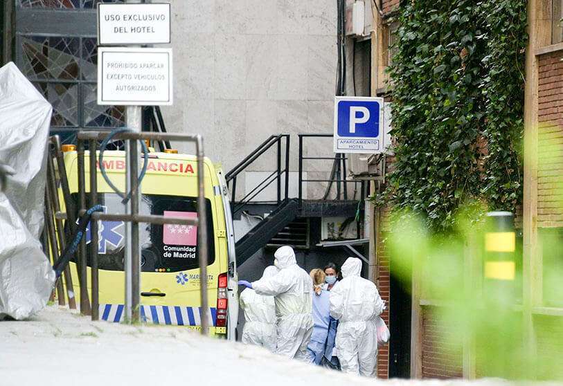 Trabajadores sanitarios con trajes protectores acompañan a un paciente a su llegada al Gran Hotel Colón de Madrid, el 19 de marzo de 2020