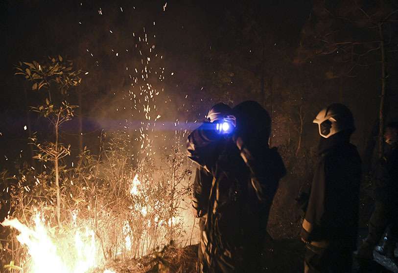 Los bomberos trabajan en la extinción de un incendio forestal en la zona de Nagarkot del distrito de Bhaktapur, a unos 32 km al norte, al este de Katmandú en la medianoche del 11 de abril de 2021