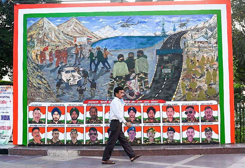 AFP/JEWEL SAMAD - Un hombre pasa junto a un cartel que muestra retratos de soldados indios muertos en un enfrentamiento cuerpo a cuerpo con militares chinos el 15 de junio de 2020