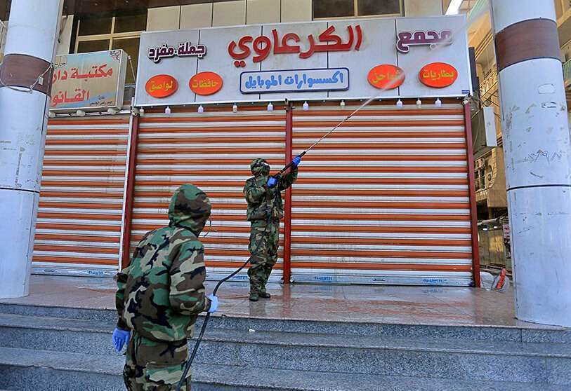 Funcionarios de salud iraquíes y personal de la Defensa Civil con trajes protectores rocían desinfectante como precaución contra el coronavirus en mercados comerciales y hoteles utilizados por ciudadanos iraníes en Najaf, Irak