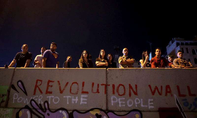 Manifestantes antigubernamentales y un soldado del Ejército libanés (R) detrás de un muro donde se lee “Muro de la Revolución” en Beirut, el 11 de noviembre de 2019