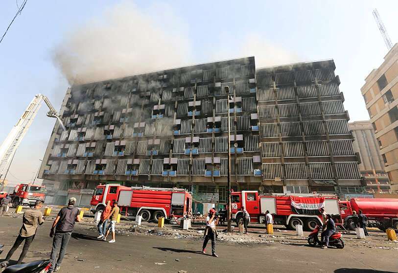 Bomberos iraquíes en el Ministerio de Finanzas incendiado por los manifestantes en la plaza Khallani de Bagdad el 11 de noviembre de 2019